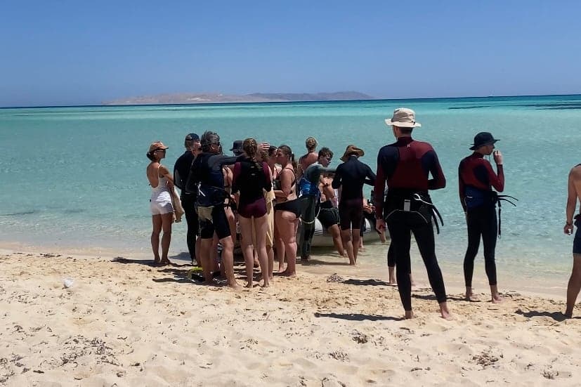 Riders gathered around an instructor for a briefing on a Red Sea sandbar