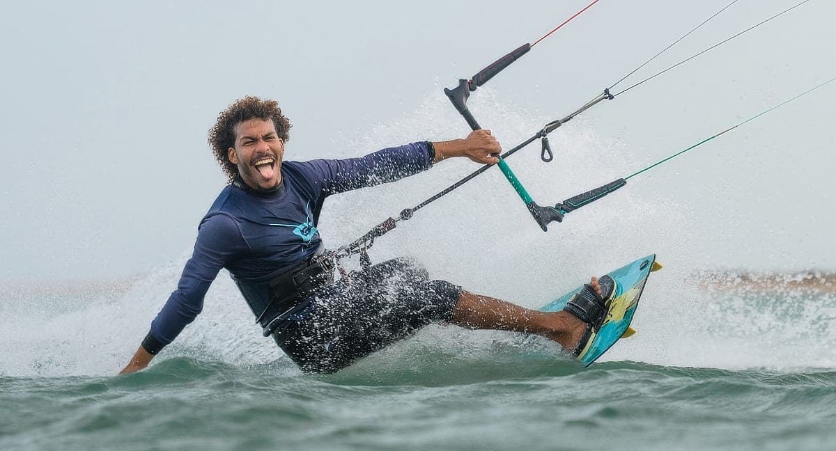 Kitesurfer laughing mid-turn through the spray on flat Red Sea water